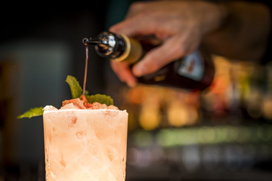 A bartender finishing a cocktail behind the bar