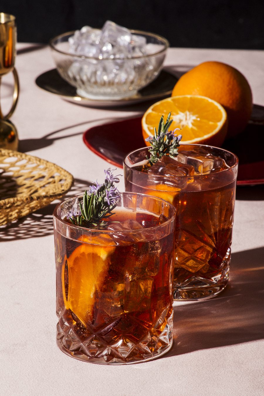 Two garnished negronis in cut-crystal glasses in afternoon sun